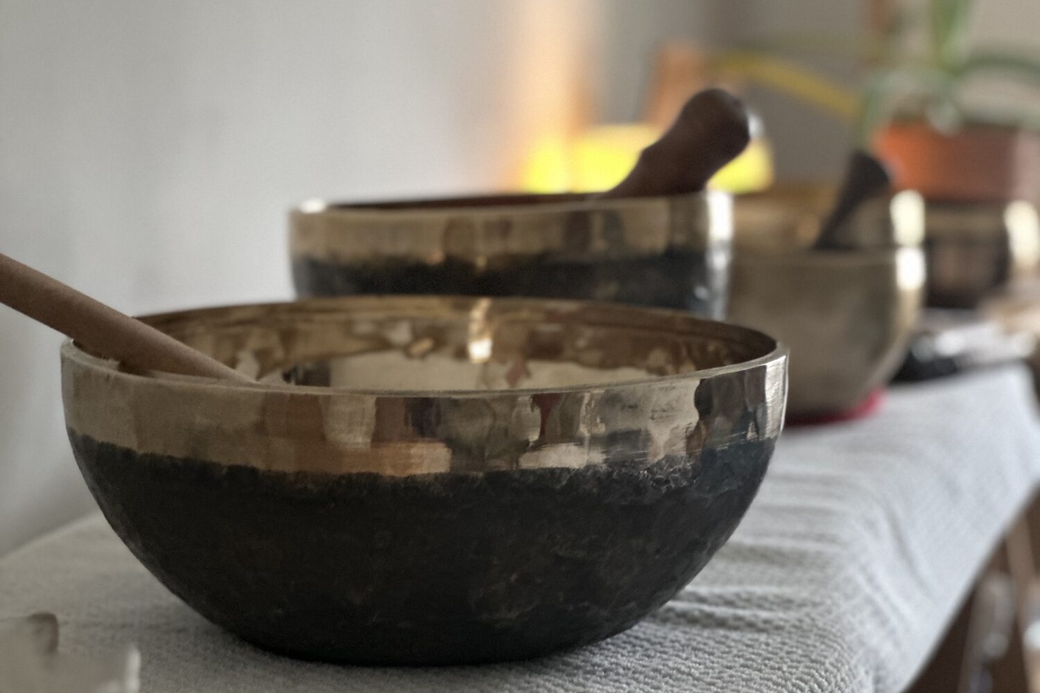 Bols tibétains alignés sur une table, à la lueur d'une bougie